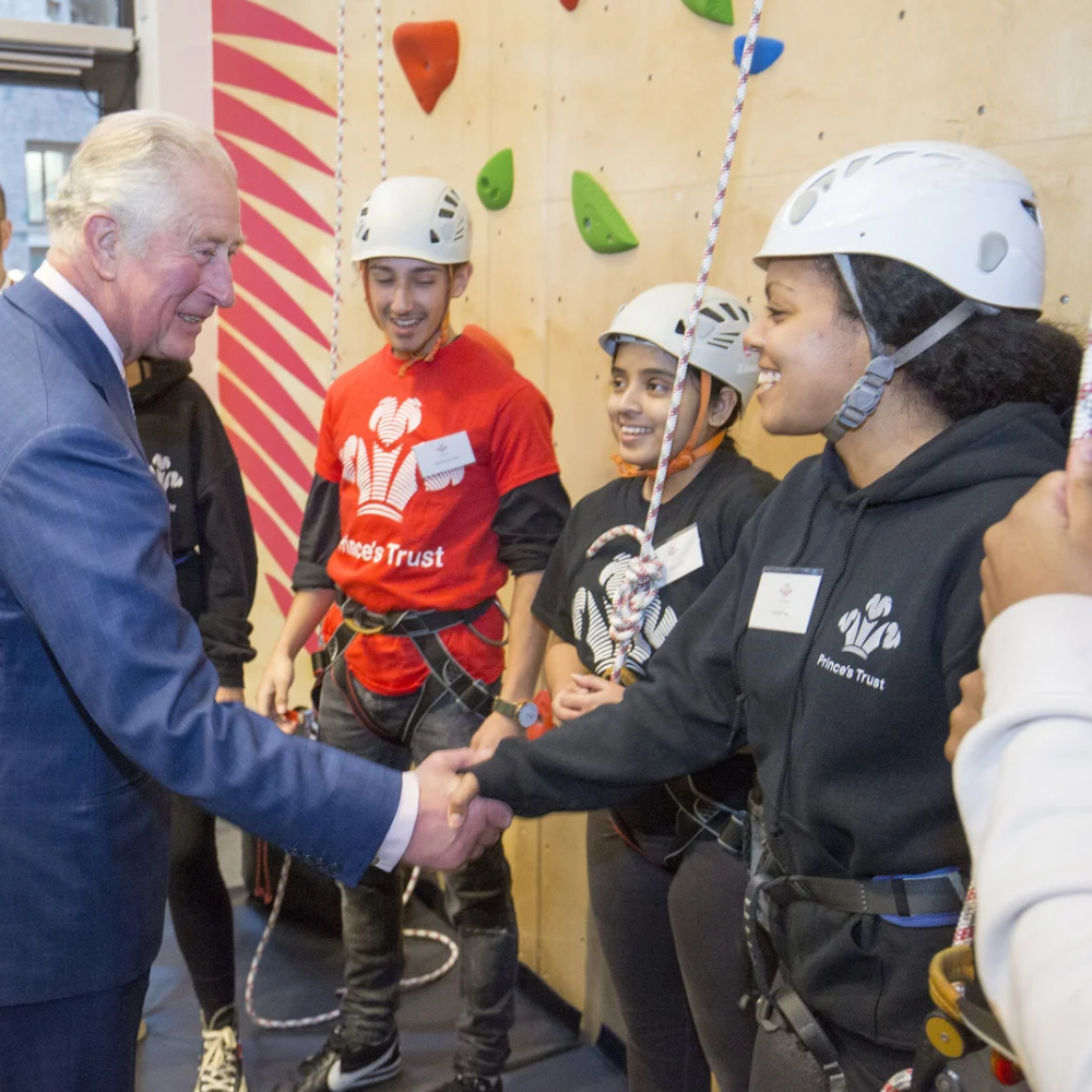 King Charles shaking hands with youth rock climbing
